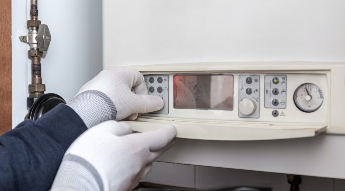 Technician servicing heating boiler in a house
